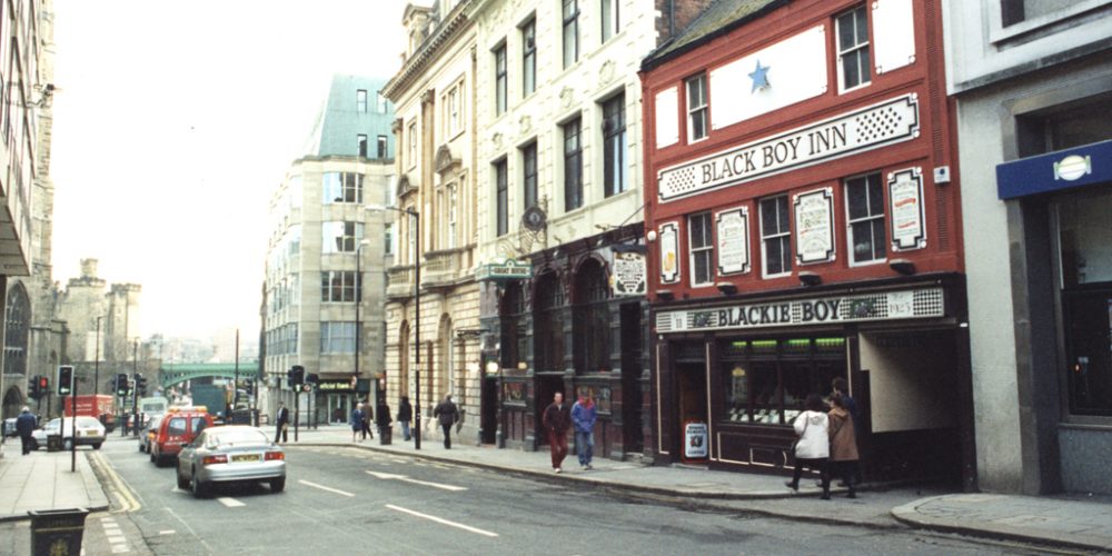 Type : Photograph Medium : Print-colour Description : A view of the Groat Market Newcastle upon Tyne taken in 1995.  An office block is on the left-hand side of the Groat Market.  On the right-hand side buildings include the 'Black Boy Inn' and the 'Groat House' pubs.  In the background to the left are St Nicholas Cathedral and the Keep. Collection : Local Studies Printed Copy : If you would like a printed copy of this image please contact Newcastle Libraries www.newcastle.gov.uk/tlt quoting Accession Number : 061941